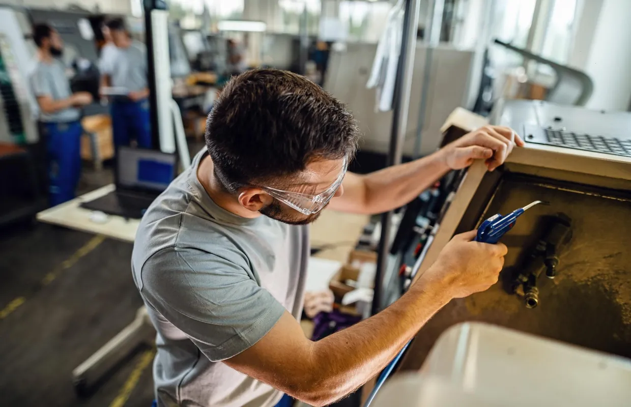 Operator in safety glasses fitting a part to a machine panel